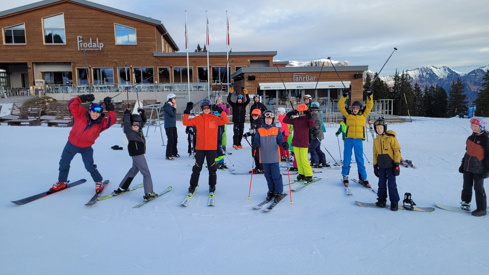 Gruppe von Skifahrern in bunter Winterkleidung vor einem Holzgebäude mit 'Prodalp' und Bergen im Hintergrund | © DAV-FN / C. Erbelding
