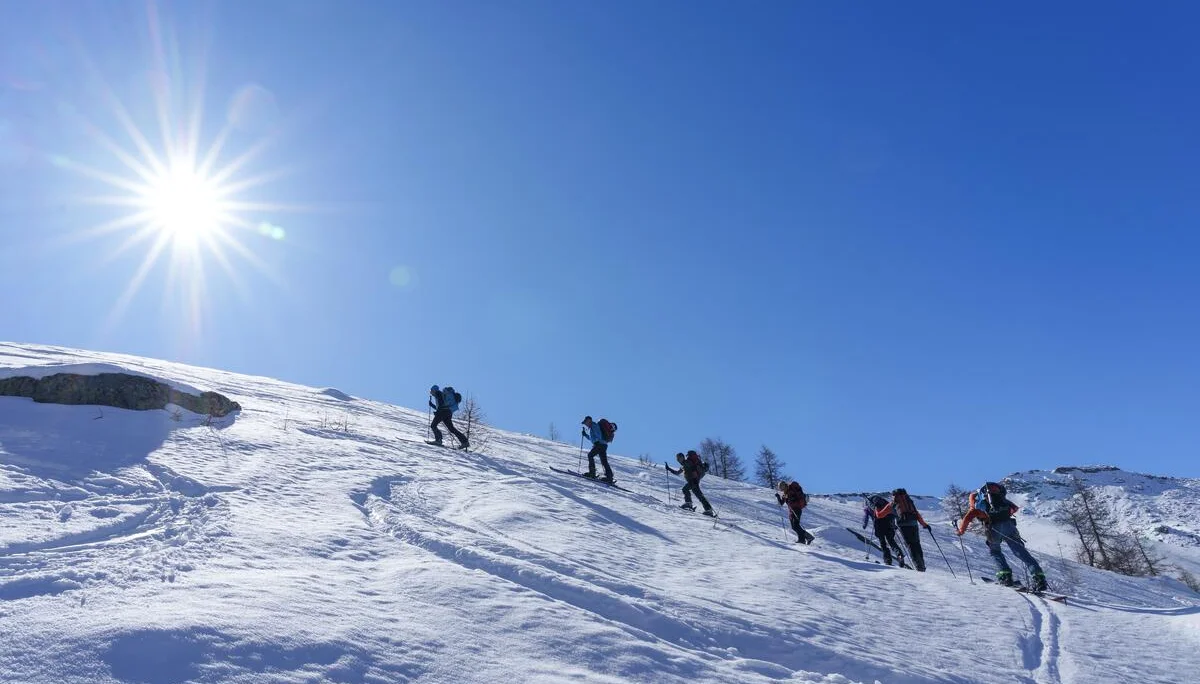 Skitourengruppe steigt bei Sonnenschein über eine verschneite Bergflanke auf. | © DAV-FN / R. Gersten u. L. Chr. Fischer