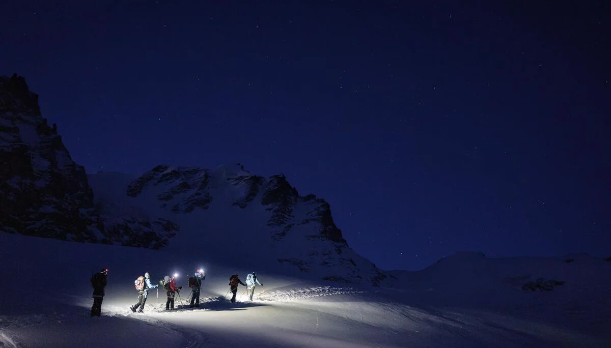 Gruppe von Wanderern mit Stirnlampen auf verschneitem Berg bei Nacht unter Sternenhimmel | © DAV-FN / R. Gersten u. L. Chr. Fischer