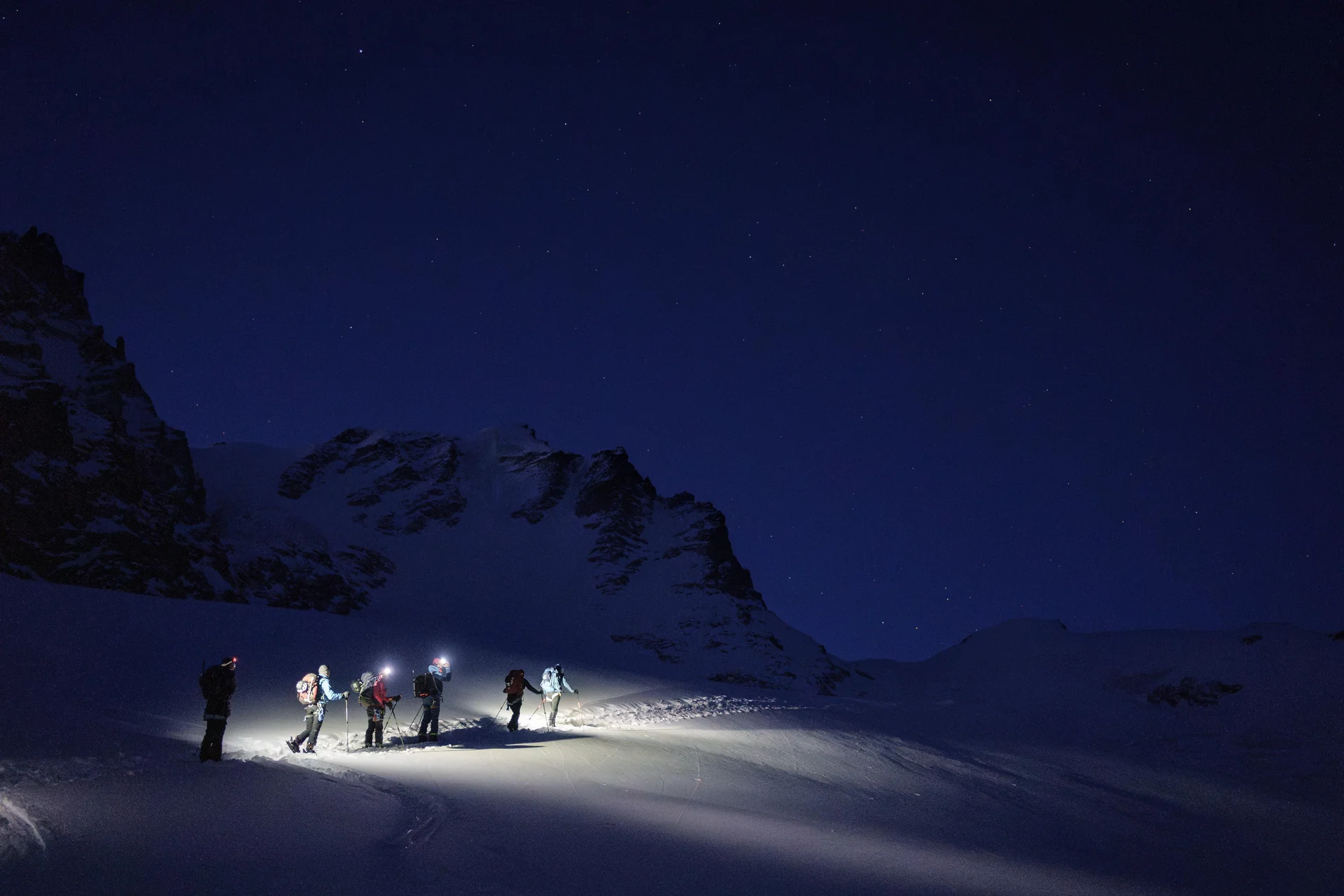 Gruppe von Wanderern mit Stirnlampen auf verschneitem Berg bei Nacht unter Sternenhimmel | © DAV-FN / R. Gersten u. L. Chr. Fischer