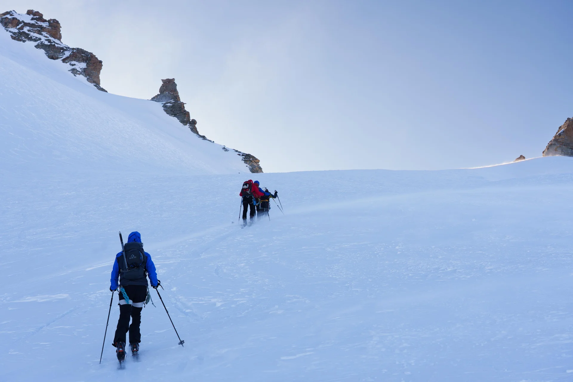Einige Skitourengeher steigen auf schneebedecktem Hang unter klarem Himmel bergauf. | © DAV-FN / R. Gersten u. L. Chr. Fischer