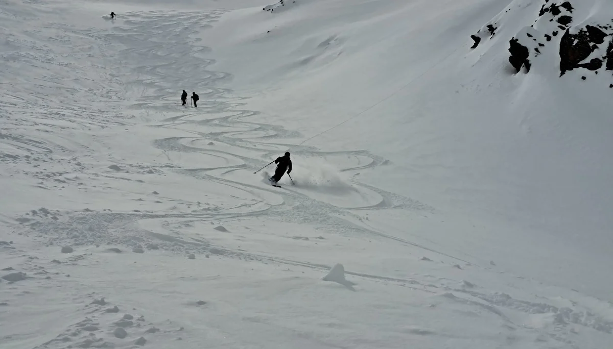 Skifahrer fährt eine verschneite Bergabfahrt an der Tiergartenspitze, zwei weitere stehen im Hintergrund | © DAV-FN / R.Lebedeff, D. Lexen