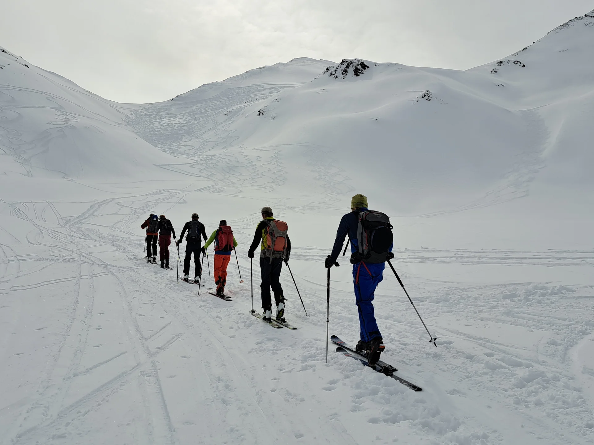 Sechs Skitourengeher mit Rucksäcken steigen in einer Reihe einen schneebedeckten Berg hinauf | © DAV-FN / R.Lebedeff, D. Lexen