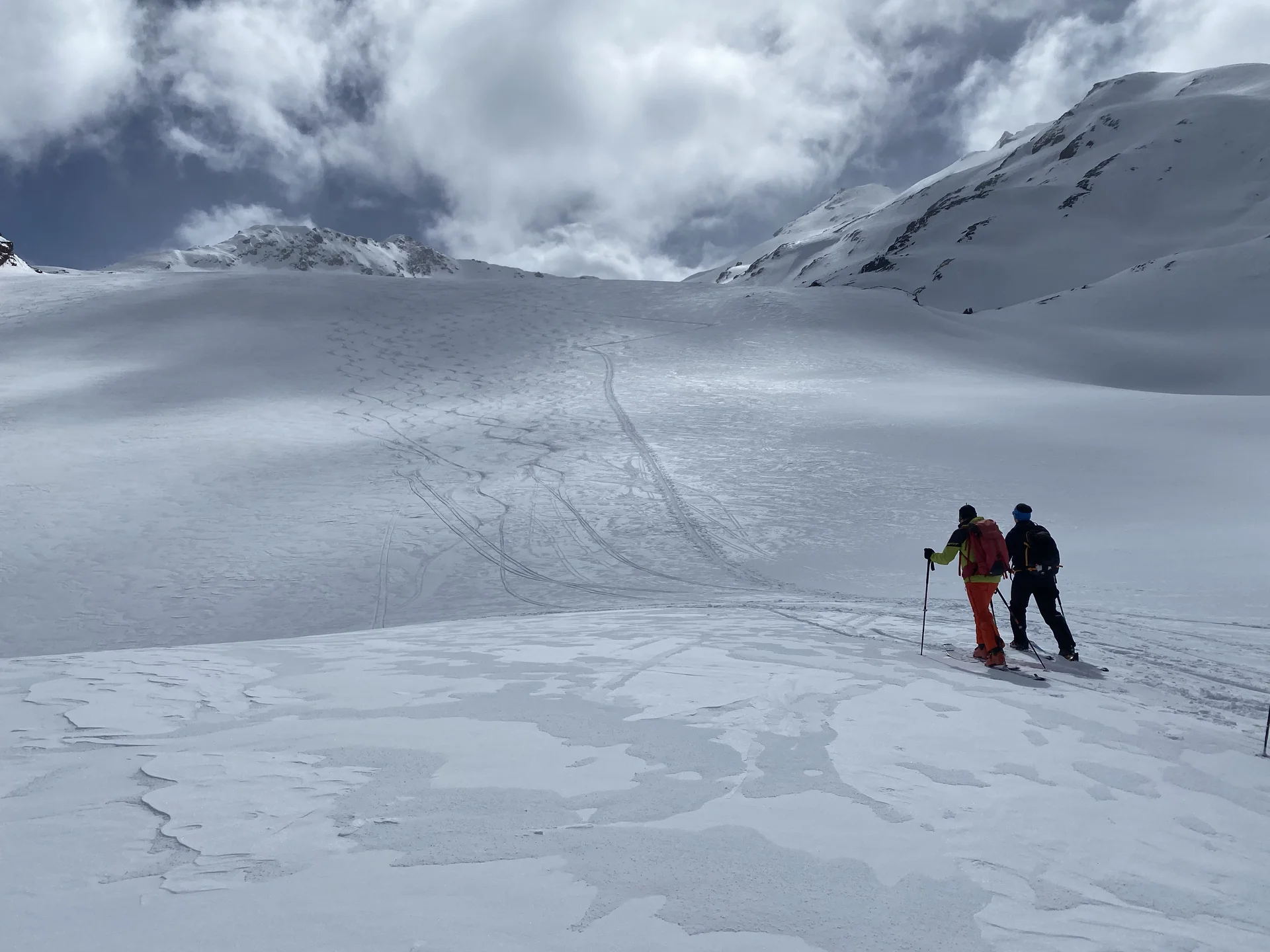 Zwei Skifahrer mit Ausrüstung stehen auf schneebedecktem Hang unter bewölktem Himmel in den Bergen | © DAV-FN / R.Lebedeff, D. Lexen