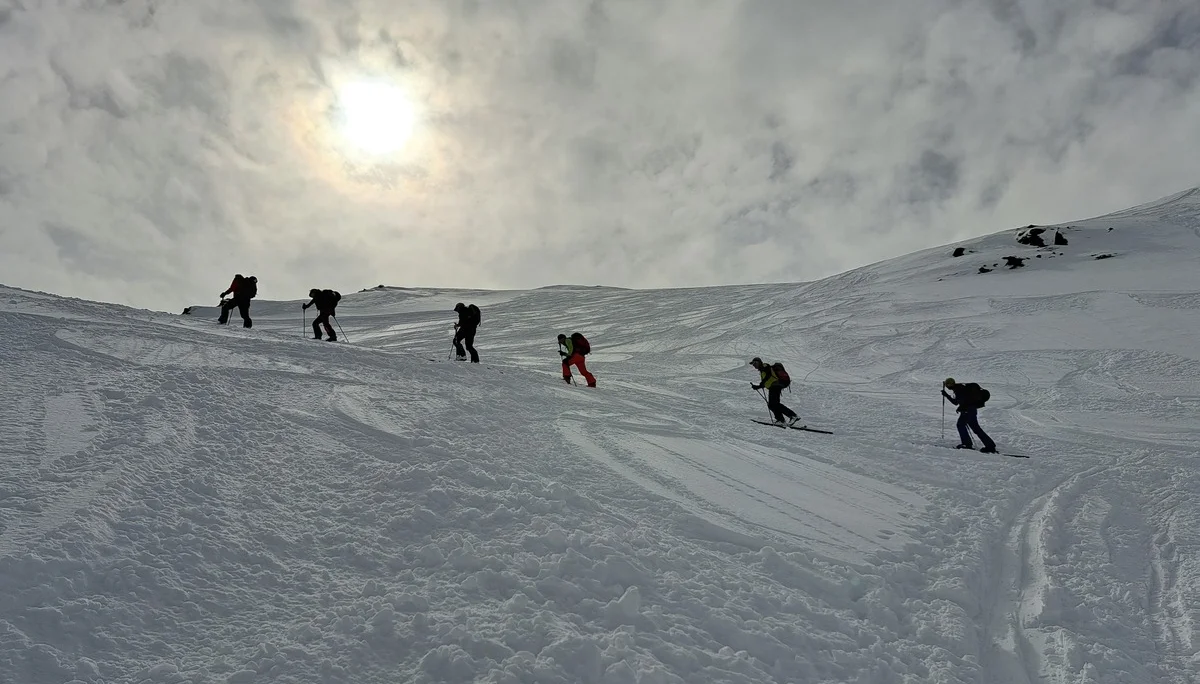 Sechs Skitourengeher steigen bei bewölktem Himmel einen schneebedeckten Hang hinauf | © DAV-FN / R.Lebedeff, D. Lexen