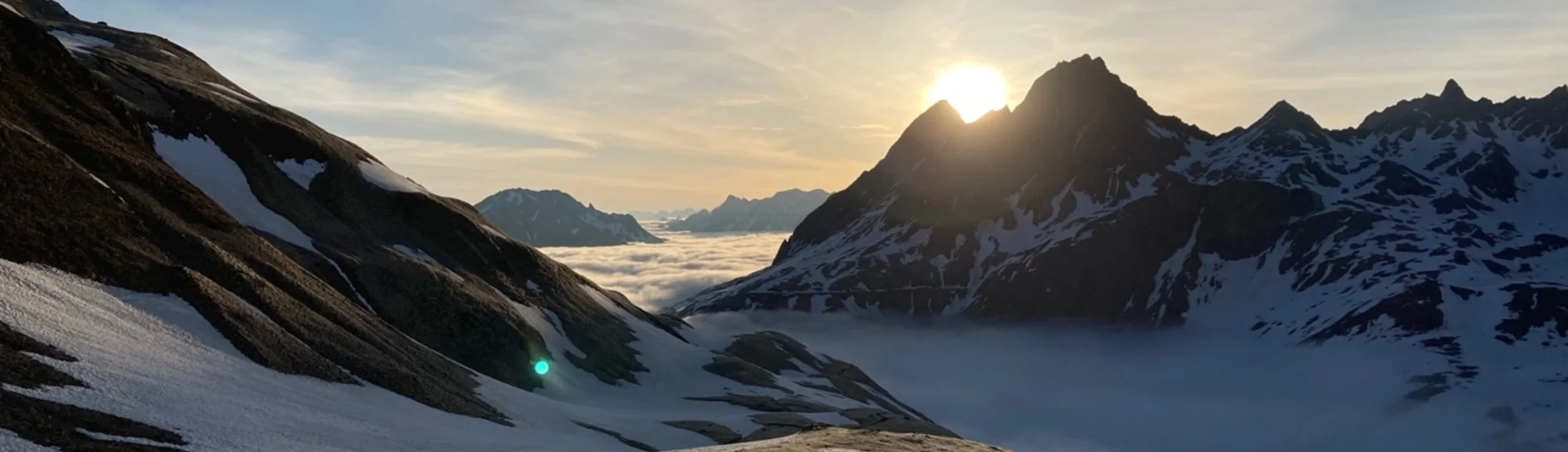 Abfahrende Skifahrer in ein nebelverhangenes Tal gegen die untergehenden Sonne | © DAV-FN / P. Schäfer