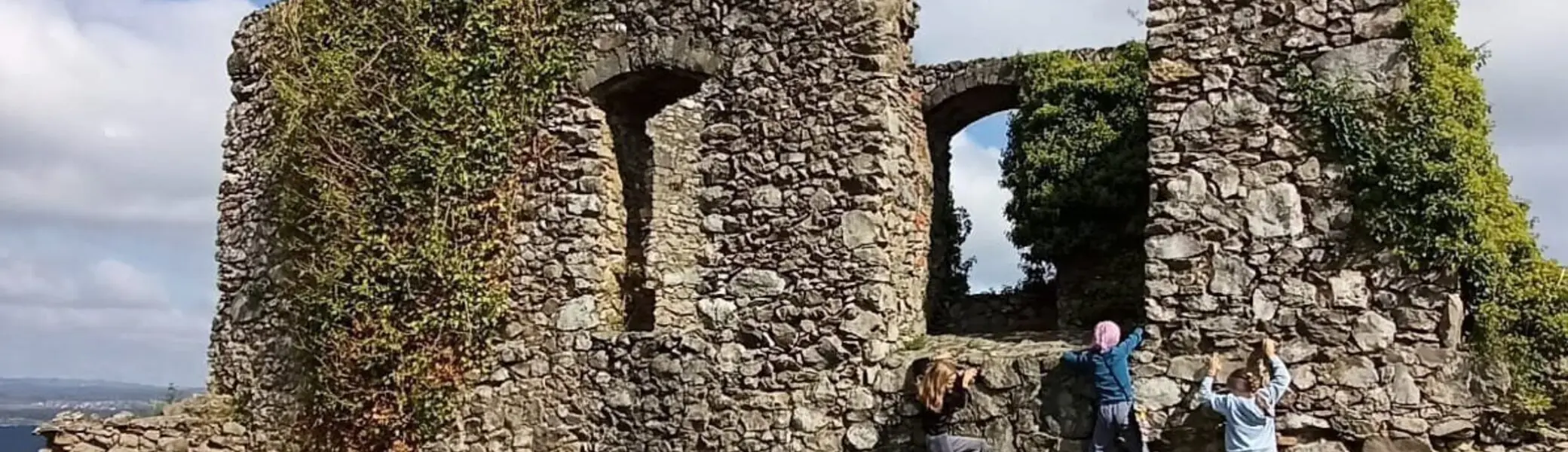 Kinder klettern an einer von Efeu bewachsenen, alten Steinruine unter blauem Himmel | © DAV-FN / M. Gross