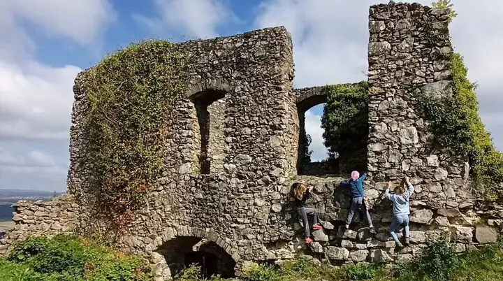 Kinder klettern an einer von Efeu bewachsenen, alten Steinruine unter blauem Himmel | © DAV-FN / M. Gross