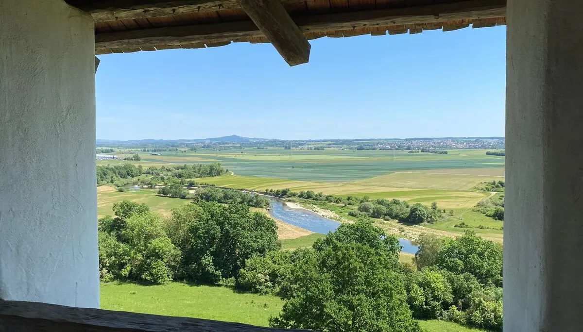 Blick aus einem Fenster mit Holzbalken auf eine Flusslandschaft mit Feldern und Bäumen unter blauem Himmel | © DAV-FN / M. Gross