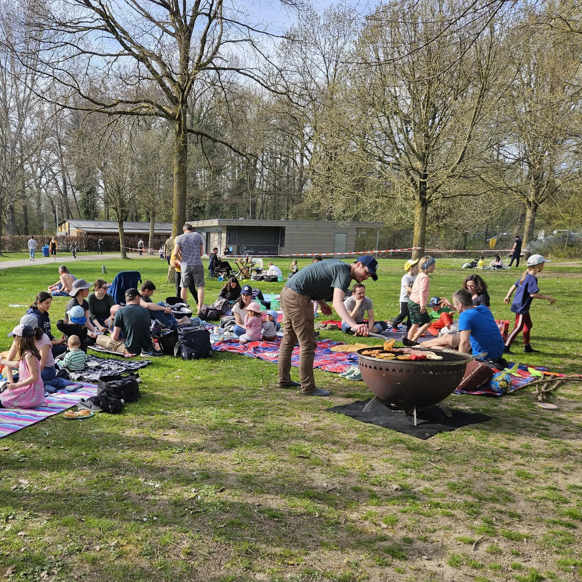 Eine Gruppe Familien beim Grillen auf einer grünen Wiese | © DAV-FN Familiengruppe