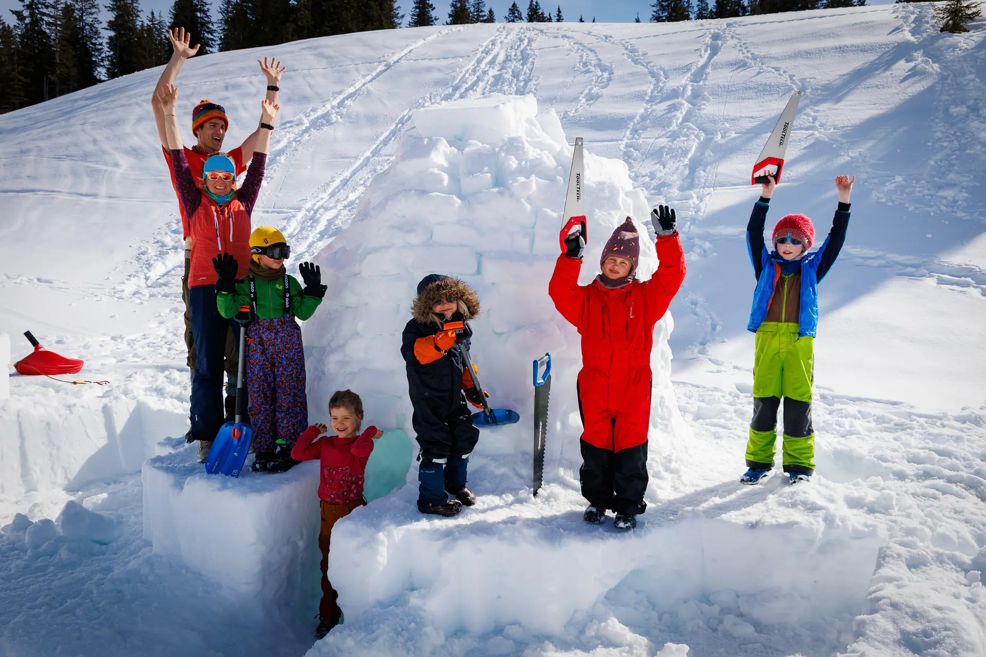 Einige Kinder mit Schneeanzügen reißen nach efolgreichem Iglubau die Arme hoch. | © DAV-FN Familiengruppe