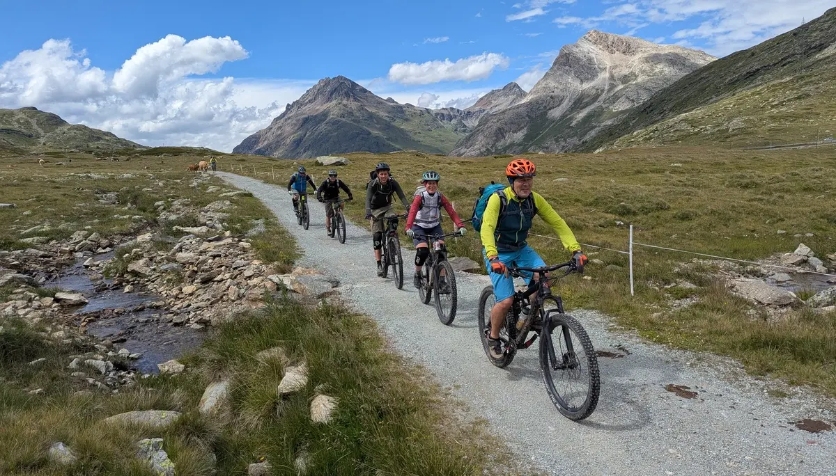 Gruppe von Radfahrern auf einem Schotterweg in bergiger Landschaft mit bewölktem Himmel | © DAV-FN / E. Flöth, M. Arzner, S. Haberer 