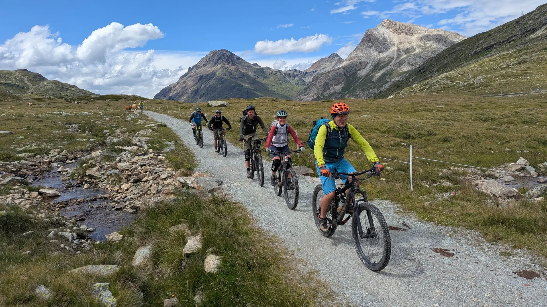 Gruppe von Radfahrern auf einem Schotterweg in bergiger Landschaft mit bewölktem Himmel | © DAV-FN / E. Flöth, M. Arzner, S. Haberer 