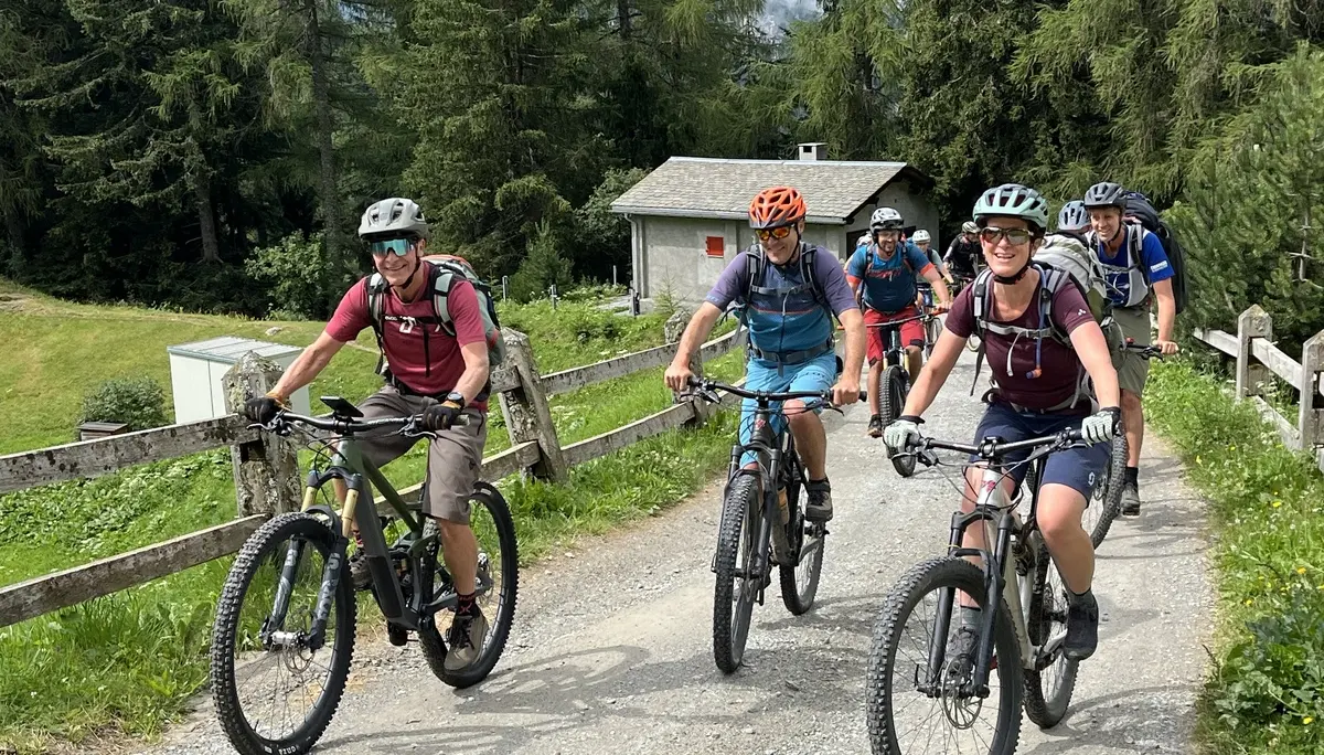Gruppe von fünf Radfahrern mit Helmen auf Mountainbikes auf einem Waldweg neben einer Holzzaun und einem kleinen Haus | © DAV-FN / E. Flöth, M. Arzner, S. Haberer 