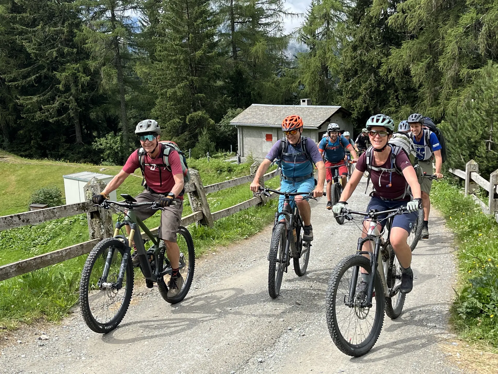 Gruppe von fünf Radfahrern mit Helmen auf Mountainbikes auf einem Waldweg neben einer Holzzaun und einem kleinen Haus | © DAV-FN / E. Flöth, M. Arzner, S. Haberer 