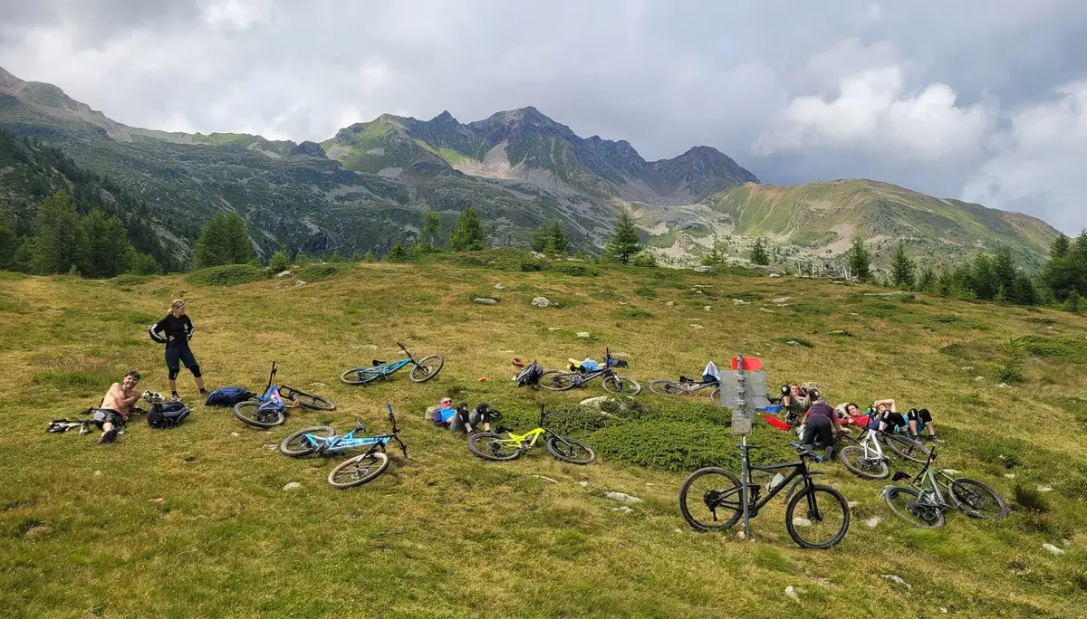 Gruppe von Menschen mit Mountainbikes auf einer Wiese vor bewaldeten Bergen unter bewölktem Himmel | © DAV-FN / E. Flöth, M. Arzner, S. Haberer 