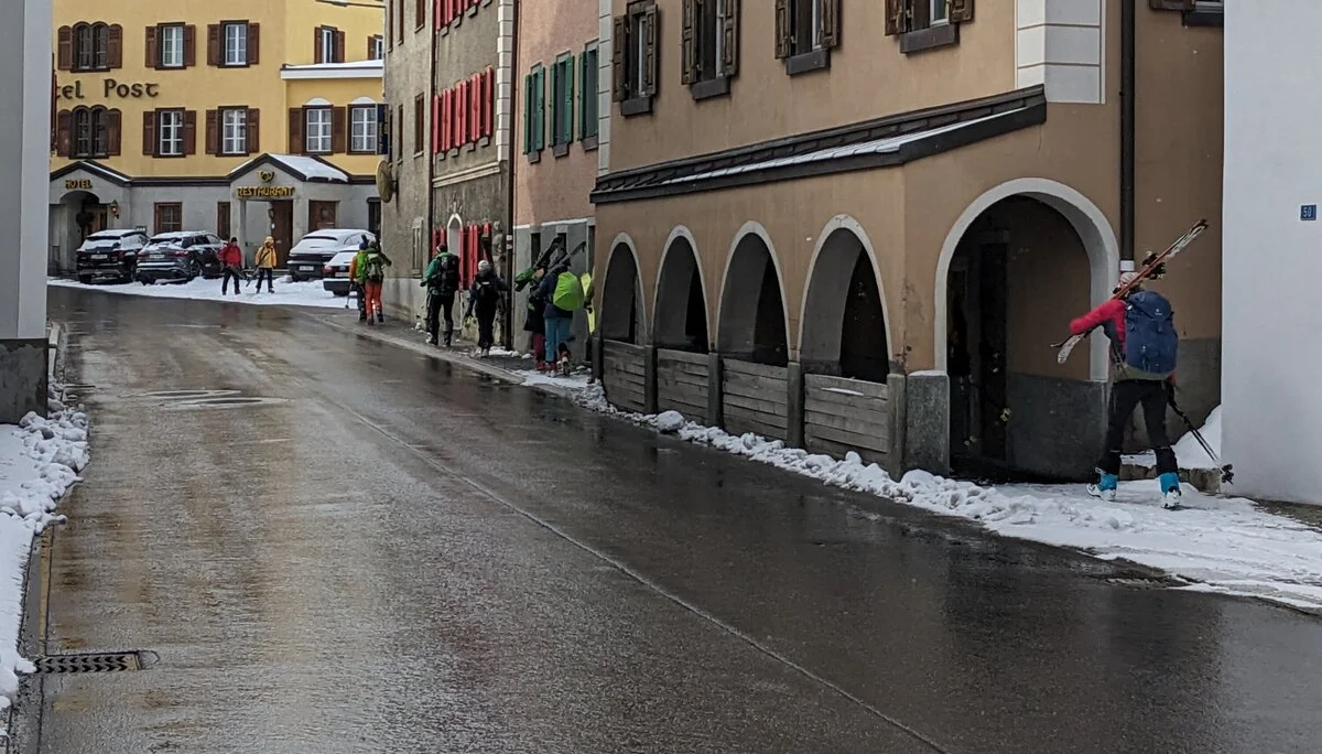 Skitourengeher tragen ihre Skier durch die Straßen von Bivio | © DAV-FN / Rucksack