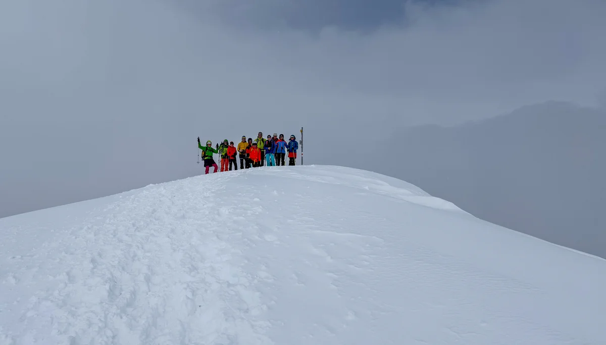 Gruppe von Skitourengehern auf einem verschneiten Hügel vor heranziehenden Wolken | © DAV-FN / Rucksack
