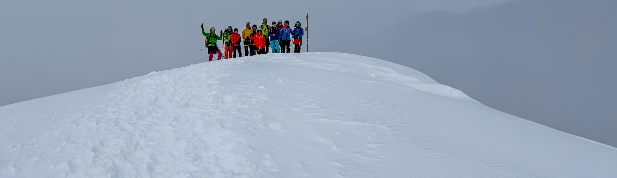 Gruppe von Skitourengehern auf einem verschneiten Hügel vor heranziehenden Wolken | © DAV-FN / Rucksack