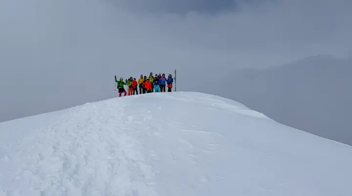 Gruppe von Skitourengehern auf einem verschneiten Hügel vor heranziehenden Wolken | © DAV-FN / Rucksack