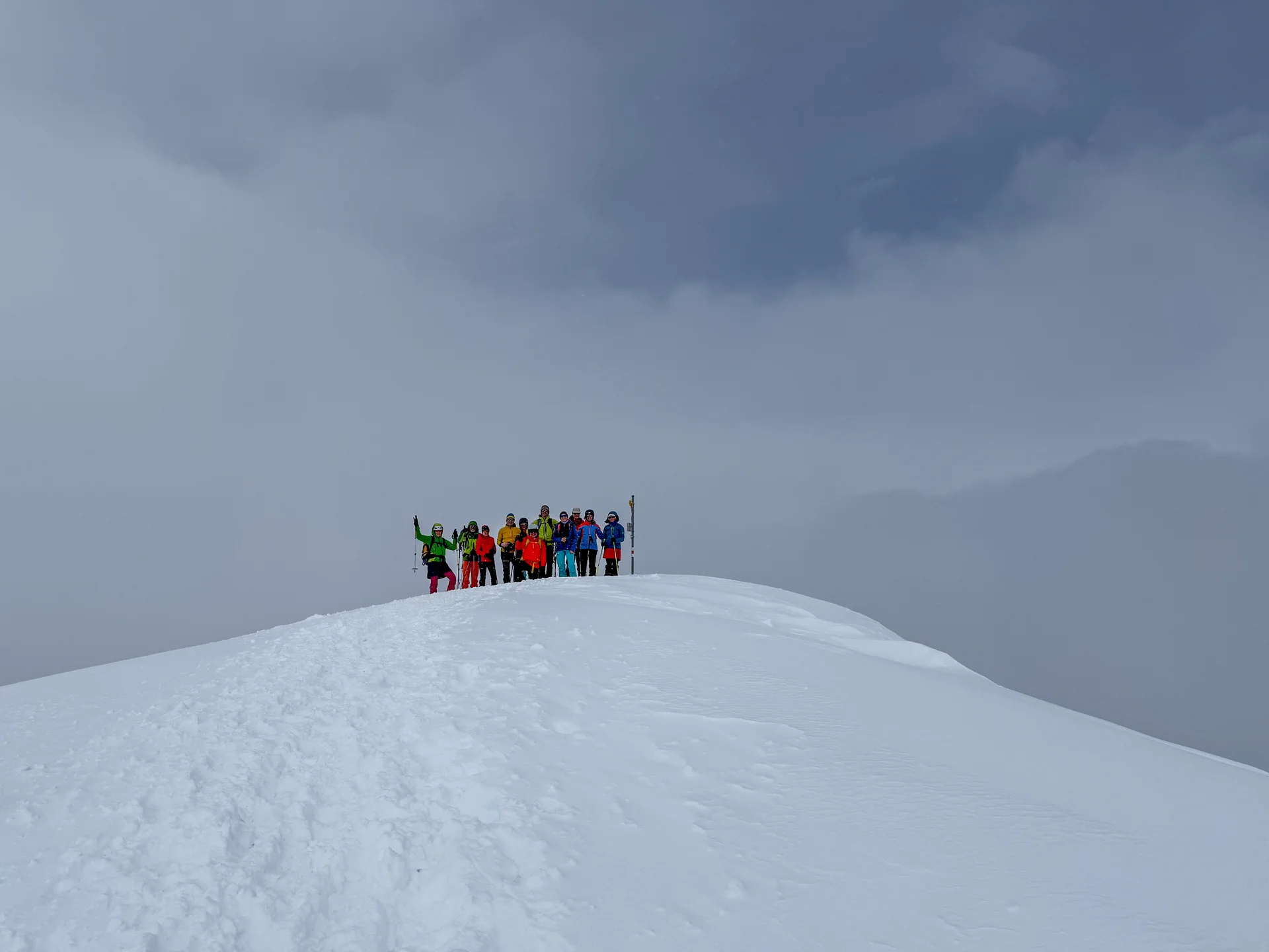 Gruppe von Skitourengehern auf einem verschneiten Hügel vor heranziehenden Wolken | © DAV-FN / Rucksack