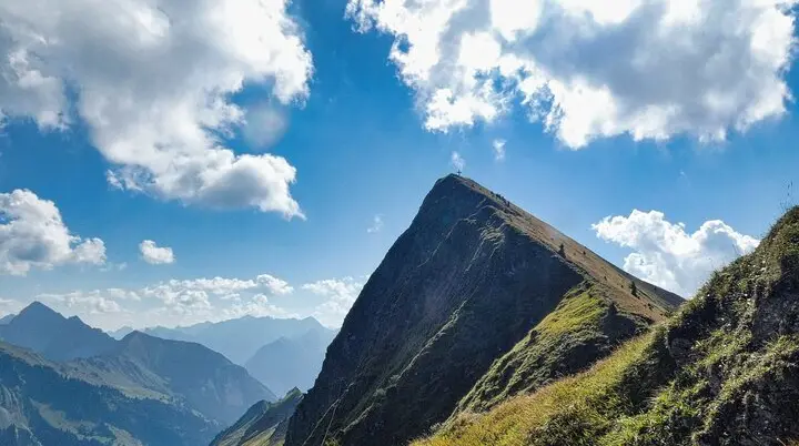 Gipfel des Glatthorn im Bregenzerwaldgebirge mit Kreuz auf dem höchsten Punkt und umliegenden Bergen unter bewölktem Himmel | © Von Steffen 962 - Eigenes Werk, CC BY-SA 4.0, auf Wikipedia