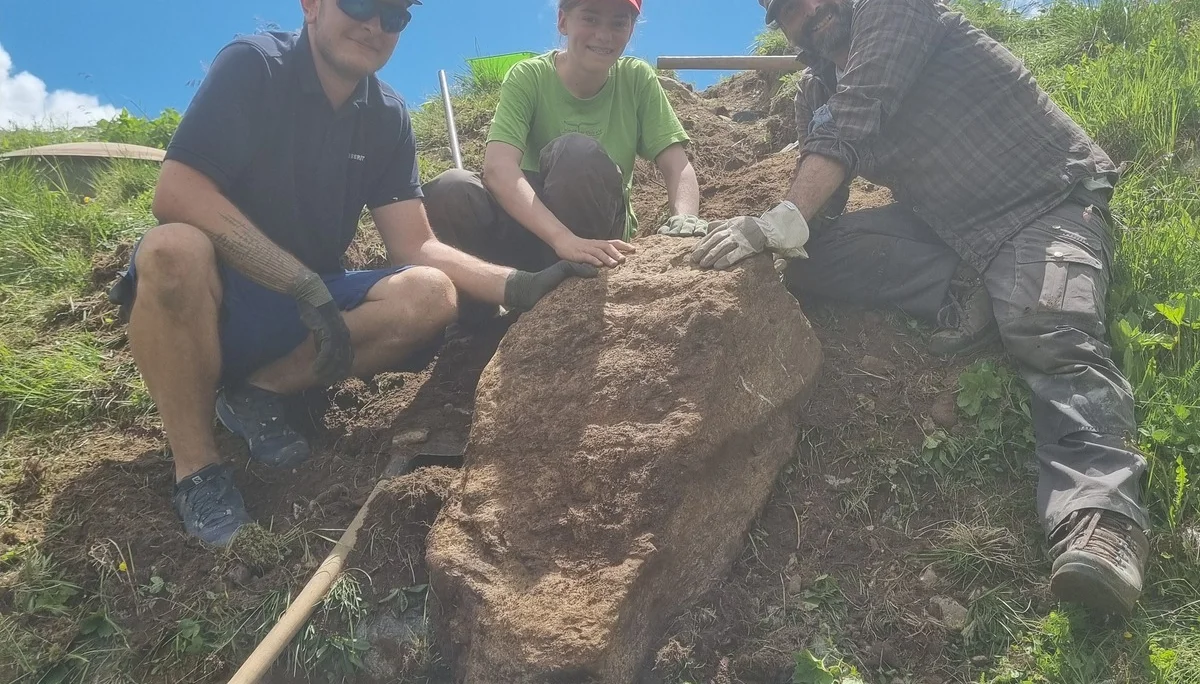 Drei Personen graben an einem Hang und heben einen großen Stein aus der Erde | © DAV-FN / R. Klees o. R. Zahner