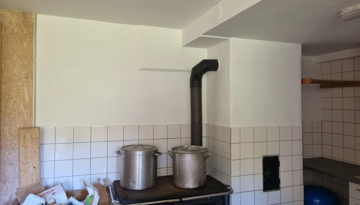 Holzherd mit zwei großen Töpfen, weiß gekachelte Wand und Ablage mit Papieren in einem rustikalen Raum | © DAV-FN / R. Klees o. R. Zahner