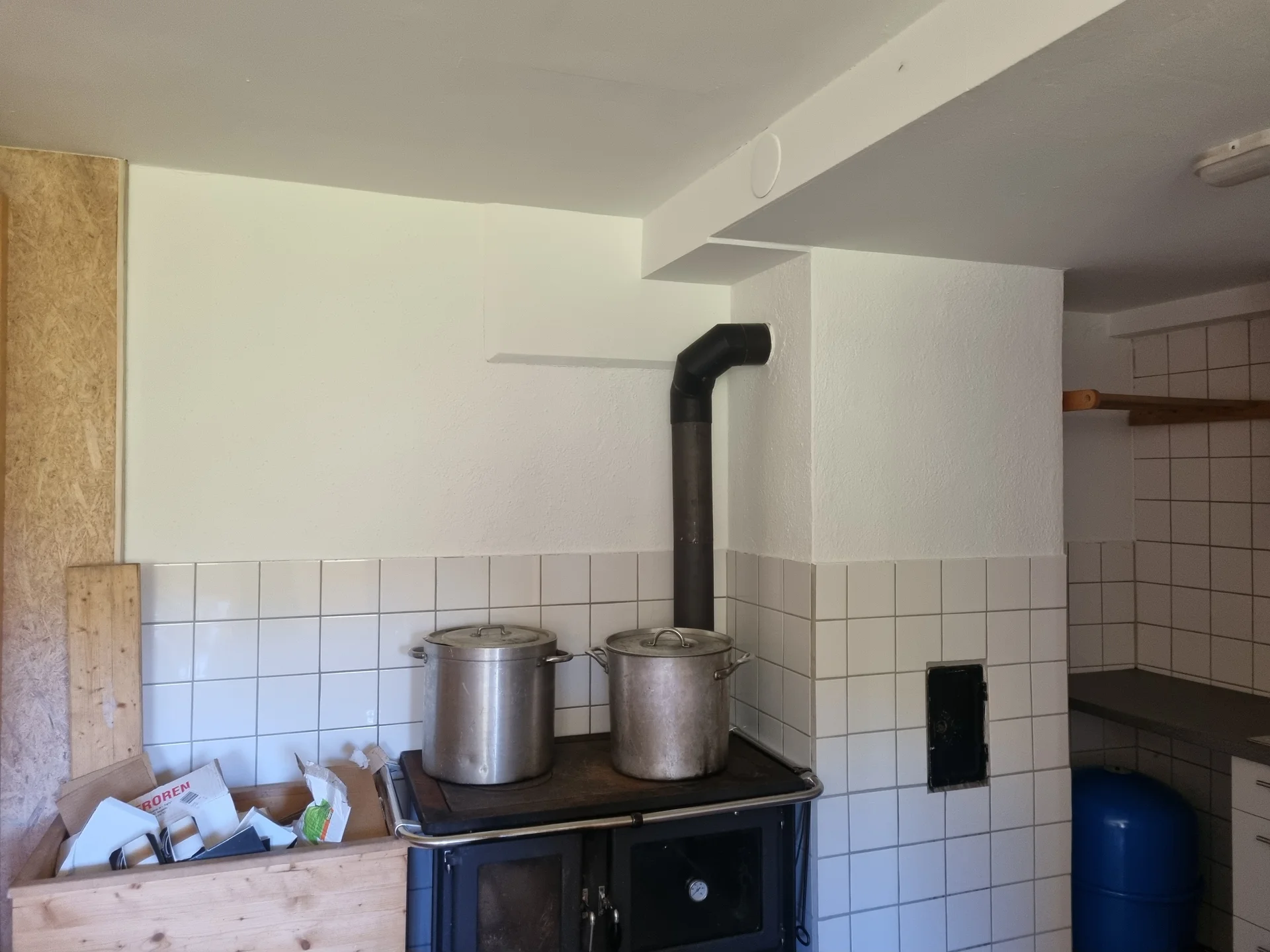 Holzherd mit zwei großen Töpfen, weiß gekachelte Wand und Ablage mit Papieren in einem rustikalen Raum | © DAV-FN / R. Klees o. R. Zahner