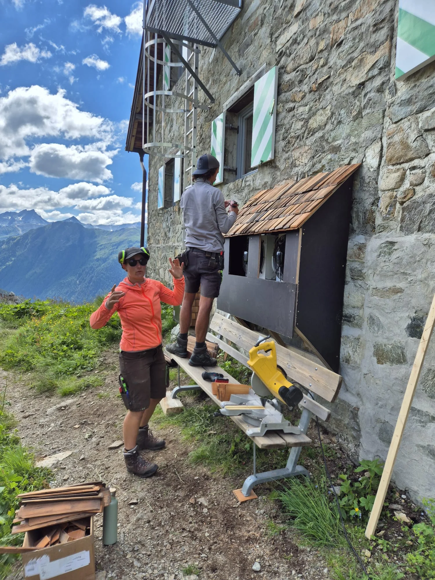 Zwei Personen arbeiten an der Holzverkleidung mit Schindeldach an der Häfler Hütte bei sonnigem Wetter | © DAV-FN / R. Klees o. R. Zahner