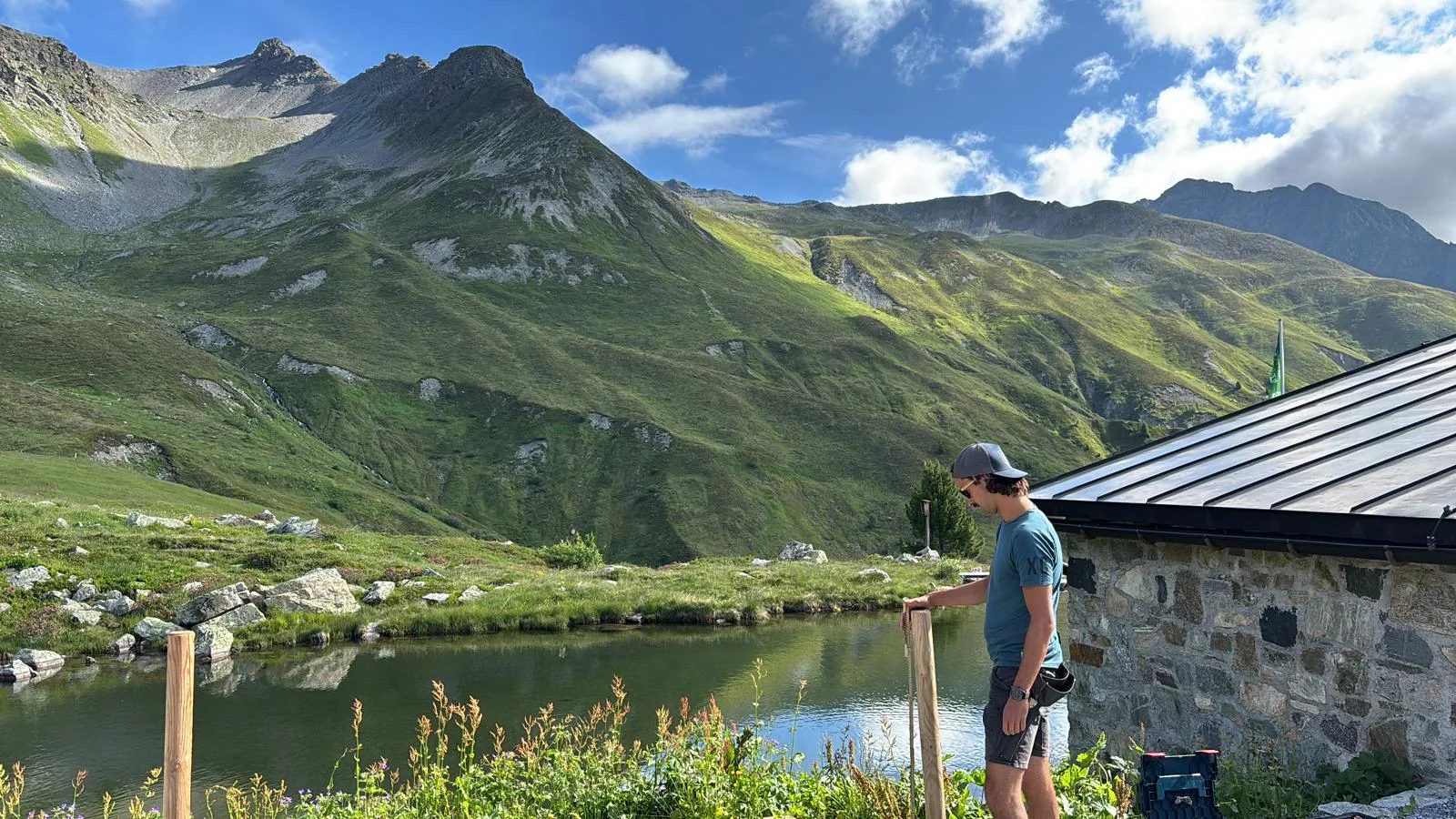 Mann mit Baseballkappe und T-Shirt steht neben einem Anbau der Häfler Hüttet am Bergsee im Verwall | © DAV-FN / R. Klees o. R. Zahner