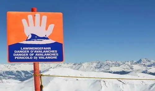 Lawinenwarnschild an einer Pistebegrenzung vor winterlichem Bergpanorama | © DAV