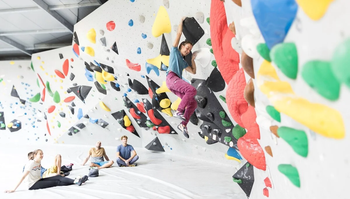 Eine Frau beim Bouldern, im Hintergrund warten weitere Personen, bis sie an der Reihe sind | © DAV / Jens Klatt